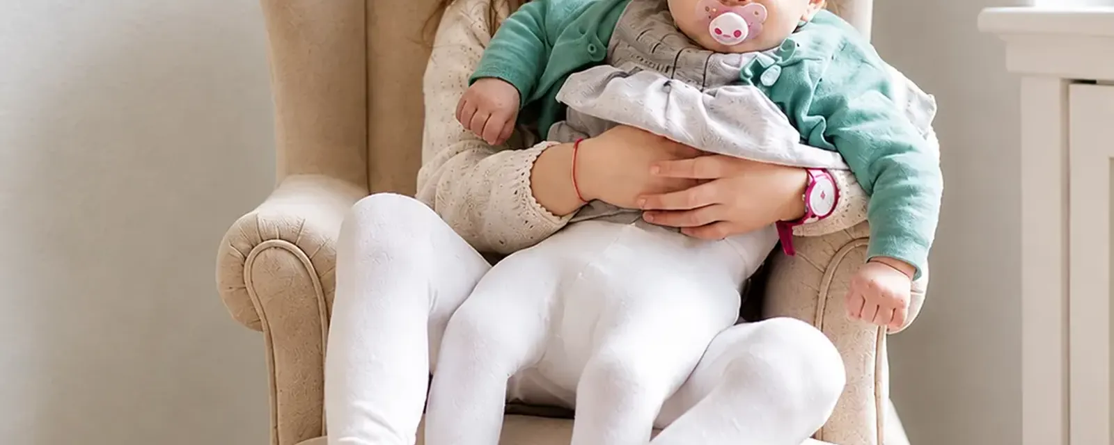 Baby wird in einem Sessel auf dem Arm gehalten
