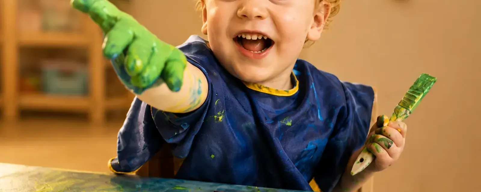 Junge malt mit Fingerfarben an einem grossen Bild